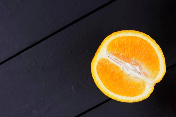 Fruits of oranges on a black wooden background, halves of oranges on wooden boards. Citrus for Vegetarian Breakfast
