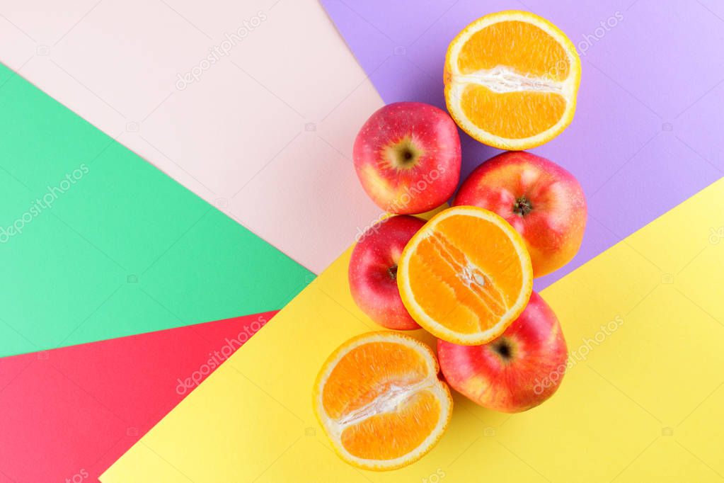 Fruits of oranges and red apples on a multicolored background, halves of oranges and apples on colored paper. Citrus in the style of pop art