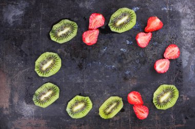 Çilek ve kivi koyu metalik üzerinde arka plan, kırmızı çilek ve kivi bir antika arka plan, vejetaryen yemek, kırmızı ve yeşil meyve üstten görünüm dilimlenmiş