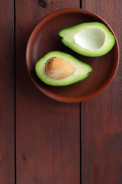 Aguacate Sobre Fondo Madera Dos Mitades Aguacate Sobre Plato Barro — Foto de Stock