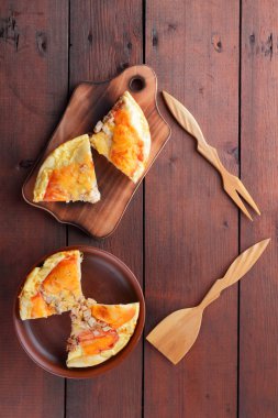 Ev yapımı pizza bir kil levha, rustik tarzı ahşap arka plan, etli sandviç ve ahşap çatal bıçak takımı, Amerikan mutfağı, sanat ile peynir doğranmış pizzaya üzerinde