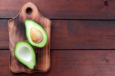Avokado üzerinde eski bir ahşap masa, avokado yarım ahşap arka plan, yeşil tropikal meyve en iyi görünüm, vintage bir arka plan üzerinde egzotik meyve üzerinde alan, etiket için boş kopyalama