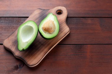 Avokado üzerinde eski bir ahşap masa, avokado yarım ahşap arka plan, yeşil tropikal meyve en iyi görünüm, vintage bir arka plan üzerinde egzotik meyve üzerinde alan, etiket için boş kopyalama