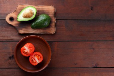 Avokado bir eski ahşap tahta, yarıya avokado ve ahşap arka plan üzerinde domates, yeşil tropikal meyve üst görüntülemek, vintage bir arka plan kopya alanı üzerinde kırmızı ve yeşil sebzeler