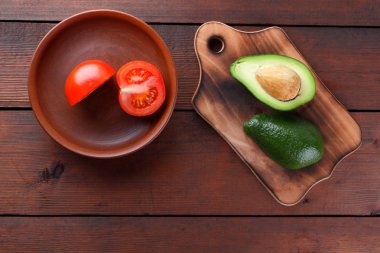 Avokado bir eski ahşap tahta, yarıya avokado ve ahşap arka plan üzerinde domates, yeşil tropikal meyve üst görüntülemek, vintage bir arka plan kopya alanı üzerinde kırmızı ve yeşil sebzeler