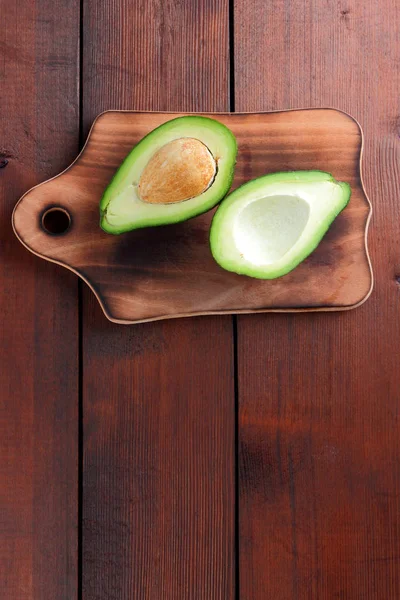 Avokado üzerinde eski bir ahşap masa, avokado yarım ahşap arka plan, yeşil tropikal meyve en iyi görünüm, vintage bir arka plan üzerinde egzotik meyve üzerinde alan, etiket için boş kopyalama