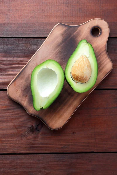 Avokado üzerinde eski bir ahşap masa, avokado yarım ahşap arka plan, yeşil tropikal meyve en iyi görünüm, vintage bir arka plan üzerinde egzotik meyve üzerinde alan, etiket için boş kopyalama