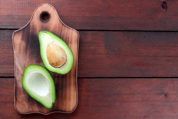 Avokado üzerinde eski bir ahşap masa, avokado yarım ahşap arka plan, yeşil tropikal meyve en iyi görünüm, vintage bir arka plan üzerinde egzotik meyve üzerinde alan, etiket için boş kopyalama
