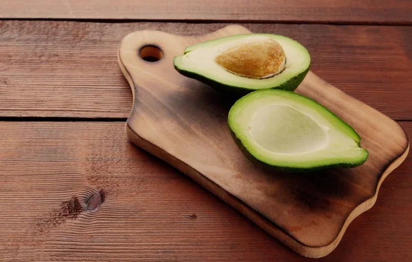 Avokado üzerinde eski bir ahşap masa, avokado yarım ahşap arka plan, yeşil tropikal meyve en iyi görünüm, vintage bir arka plan üzerinde egzotik meyve üzerinde alan, etiket için boş kopyalama