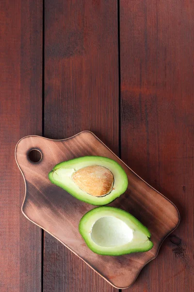 Avokado üzerinde eski bir ahşap masa, avokado yarım ahşap arka plan, yeşil tropikal meyve en iyi görünüm, vintage bir arka plan üzerinde egzotik meyve üzerinde alan, etiket için boş kopyalama