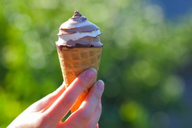 Dondurma koni elinde, çikolatalı dondurma arka plan bulanık, süt tatlı yaz tatili, tasarımcı için kopya alanı boş üzerinde