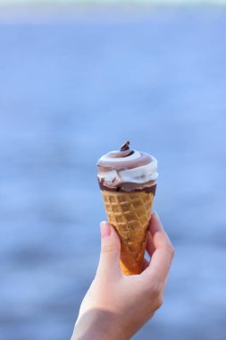 Dondurma koni elinde, çikolatalı dondurma arka plan bulanık, süt tatlı yaz tatili, tasarımcı için kopya alanı boş üzerinde