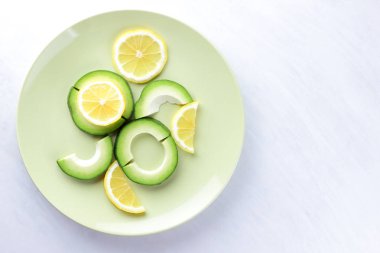 Avokado ve limon bir yeşil plaka, beyaz arka plan, Vejetaryen gıda, yararlı doğal gıda, tropik meyveler avokado kahvaltı için dilimlenmiş, kopyalama alanı