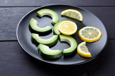 Avokado siyah plaka tepesinde görüntülemek, avokado ve limon siyah ahşap panoları, Vejetaryen gıda, yararlı doğal gıda, tropik meyveler kahvaltıda dilimlenmiş, alanı Kopyala