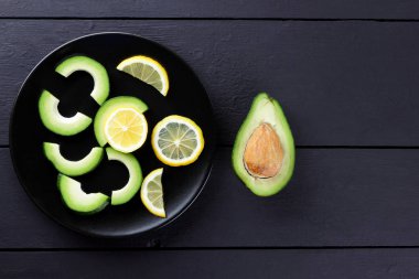 Avokado siyah plaka tepesinde görüntülemek, avokado ve limon siyah ahşap panoları, Vejetaryen gıda, yararlı doğal gıda, tropik meyveler kahvaltıda dilimlenmiş, alanı Kopyala