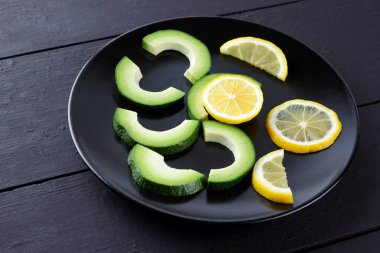 Avokado siyah plaka tepesinde görüntülemek, avokado ve limon siyah ahşap panoları, Vejetaryen gıda, yararlı doğal gıda, tropik meyveler kahvaltıda dilimlenmiş, alanı Kopyala