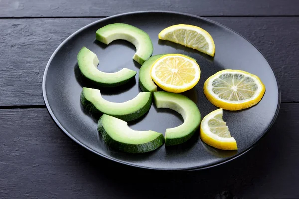 Avokado siyah plaka tepesinde görüntülemek, avokado ve limon siyah ahşap panoları, Vejetaryen gıda, yararlı doğal gıda, tropik meyveler kahvaltıda dilimlenmiş, alanı Kopyala