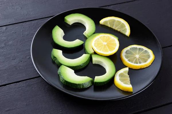 Avokado siyah plaka tepesinde görüntülemek, avokado ve limon siyah ahşap panoları, Vejetaryen gıda, yararlı doğal gıda, tropik meyveler kahvaltıda dilimlenmiş, alanı Kopyala