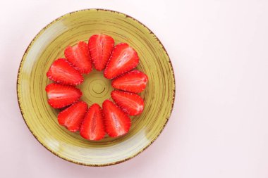 Sarı bir tabak, çizgili kırmızı çilek yarım daire üstten görünüm, beyaz bir arka planda, vejetaryen yemek kahvaltı için kırmızı çilek çilek kopyalama alanı, sağlıklı gıda, diyet