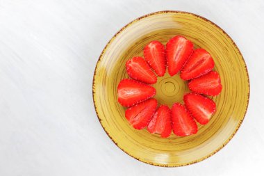 Sarı bir tabak, çizgili kırmızı çilek yarım daire üstten görünüm, beyaz bir arka planda, vejetaryen yemek kahvaltı için kırmızı çilek çilek kopyalama alanı, sağlıklı gıda, diyet