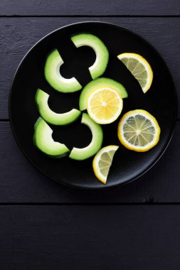 Avokado ve limon siyah ahşap panoları, vejetaryen yemek, yararlı doğal gıda, dilimlenmiş siyah plaka üstten görünüm üzerinde avokado tropikal meyveler Kahvaltı, Şili gıda, kopya alanı için