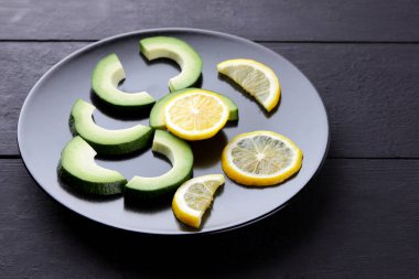 Avokado ve limon siyah ahşap panoları, vejetaryen yemek, yararlı doğal gıda, dilimlenmiş siyah plaka üstten görünüm üzerinde avokado tropikal meyveler Kahvaltı, Şili gıda, kopya alanı için