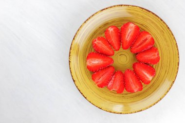 Sarı bir tabak, çizgili kırmızı çilek yarım daire üstten görünüm, beyaz bir arka planda, vejetaryen yemek kahvaltı için kırmızı çilek çilek alanı, tasarımcı için boş kopyalama
