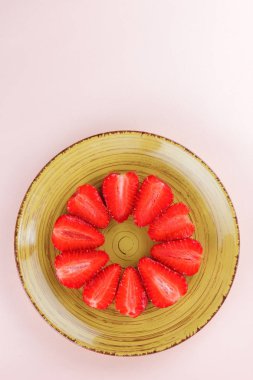 Sarı bir tabak, çizgili kırmızı çilek yarım daire üstten görünüm, beyaz bir arka planda, vejetaryen yemek kahvaltı için kırmızı çilek çilek alanı, tasarımcı için boş kopyalama