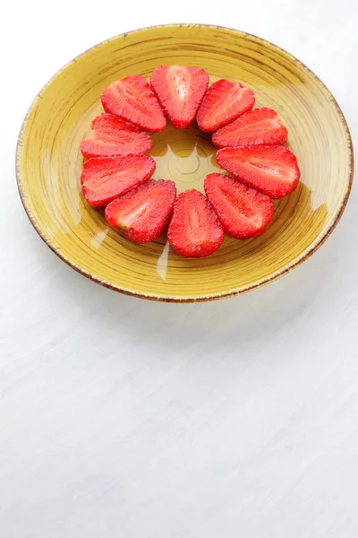 Sarı bir tabak, çizgili kırmızı çilek yarım daire üstten görünüm, beyaz bir arka planda, vejetaryen yemek kahvaltı için kırmızı çilek çilek alanı, tasarımcı için boş kopyalama