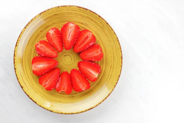 Sarı bir tabak, çizgili kırmızı çilek yarım daire üstten görünüm, beyaz bir arka planda, vejetaryen yemek kahvaltı için kırmızı çilek çilek alanı, tasarımcı için boş kopyalama