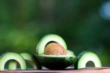 Avokado bulanık yeşil bokeh arka plan, bir ahşap masa, egzotik meyve salatası, vejetaryen yemek, Meksika yemeği, organik, üzerinde kesme avokado kopyalama alanı