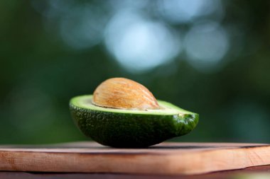 Avokado bulanık yeşil bokeh arka plan, bir ahşap masa, egzotik meyve salatası, vejetaryen yemek, Meksika yemeği, organik, üzerinde kesme avokado kopyalama alanı