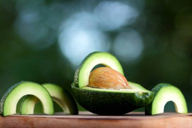 Avokado bulanık yeşil bokeh arka plan, bir ahşap masa, egzotik meyve salatası, vejetaryen yemek, Meksika yemeği, organik, üzerinde kesme avokado kopyalama alanı
