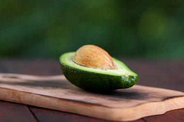 Avokado bulanık yeşil bokeh arka plan, bir ahşap masa, egzotik meyve salatası, vejetaryen yemek, Meksika yemeği, organik, üzerinde kesme avokado kopyalama alanı