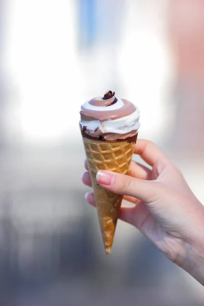 Ice cream cone, chocolate ice cream on blurred background, milk dessert on summer vacation, blank for designer with hand, copy space, milk product