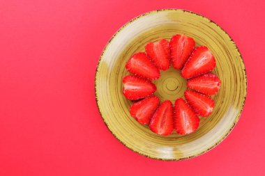 Çilek kırmızı bir arka plan, bir daire, vejetaryen yemek kahvaltı için sarı bir tabakta kırmızı meyveler şeklinde kırmızı çilek yarısı Tarih alanı, bir tasarımcı için yaratıcı boş kopyalama