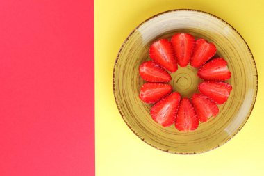 Çilek kırmızı bir arka plan, bir daire, vejetaryen yemek kahvaltı için sarı bir tabakta kırmızı meyveler şeklinde kırmızı çilek yarısı Tarih alanı, bir tasarımcı için yaratıcı boş kopyalama