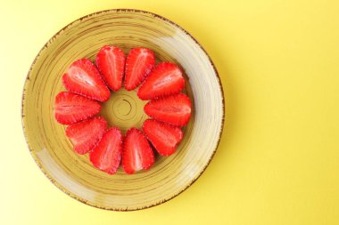 Çilek sarı bir arka plan bir daire, vejetaryen yemek kahvaltı için sarı bir tabakta kırmızı meyveler şeklinde kırmızı çilek yarısı Tarih alanı, bir tasarımcı için yaratıcı boş kopyalama