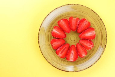 Çilek sarı bir arka plan bir daire, vejetaryen yemek kahvaltı için sarı bir tabakta kırmızı meyveler şeklinde kırmızı çilek yarısı Tarih alanı, bir tasarımcı için yaratıcı boş kopyalama