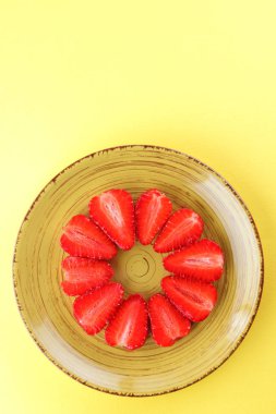 Çilek sarı bir arka plan bir daire, vejetaryen yemek kahvaltı için sarı bir tabakta kırmızı meyveler şeklinde kırmızı çilek yarısı Tarih alanı, bir tasarımcı için yaratıcı boş kopyalama