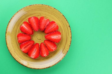 Çilek yeşil bir arka planda bir daire, vejetaryen yemek kahvaltı için sarı bir tabakta kırmızı meyveler şeklinde kırmızı çilek yarısı alanı, bir tasarımcı için yaratıcı boş kopyalama