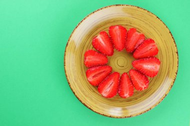 Çilek yeşil bir arka planda bir daire, vejetaryen yemek kahvaltı için sarı bir tabakta kırmızı meyveler şeklinde kırmızı çilek yarısı alanı, bir tasarımcı için yaratıcı boş kopyalama