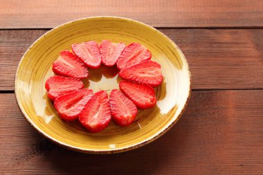 Alan, bir tasarımcı için yaratıcı boş ahşap kurullarında, yarısı bir daire, vejetaryen yemek kahvaltı için sarı bir tabakta kırmızı meyveler şeklinde kırmızı çilek çilek kopyalama