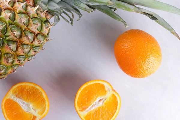 Pineapple and oranges on white background, citrus top view, cut oranges for fruit salad, vegetarian food, tropical fruits for diet, copy space