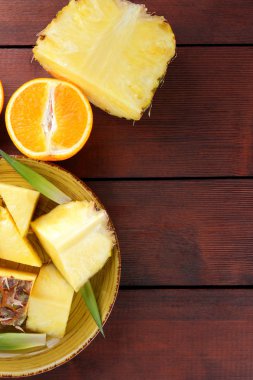 Ananas ve portakal ahşap panoları, ananas ve portakal ahşap zemin, kahvaltıda vejetaryen yemek, tropikal meyve salatası yarısı sarı bir tabakta alanı Kopyala