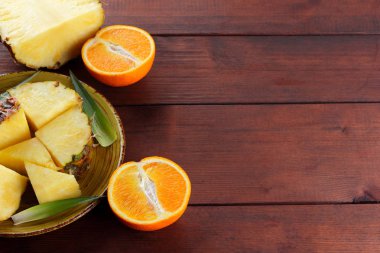 Ananas ve portakal ahşap panoları, ananas ve portakal ahşap zemin, kahvaltıda vejetaryen yemek, tropikal meyve salatası yarısı sarı bir tabakta alanı Kopyala