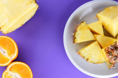 Ananas ve portakal beyaz bir tabak, doğranmış ananas ve menekşe arka plan, tropikal meyveler kahvaltıda vejetaryen yemek, salata üzerinde yarım portakal parçaları alanı Kopyala