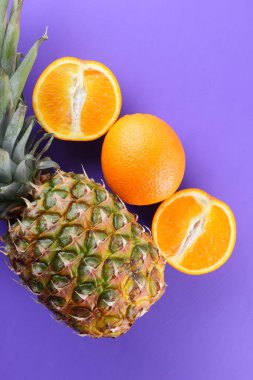 Ananas ve portakal mor bir arka plan, narenciye üstten görünüm, ananas ve portakal pop sanat tarzı, vejetaryen yemek, meyve salatası yarısı