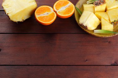 Ananas ve portakal ahşap panoları, ananas ve portakal ahşap zemin, kahvaltı için tropikal meyve salatası yarısı sarı bir plaka üzerinde parçalar
