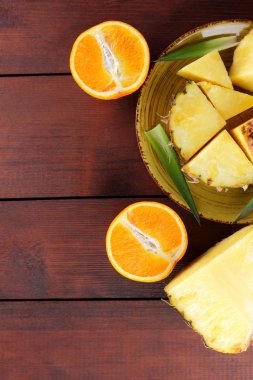 Ananas ve portakal ahşap panoları, ananas ve portakal ahşap zemin, kahvaltı için tropikal meyve salatası yarısı sarı bir plaka üzerinde parçalar